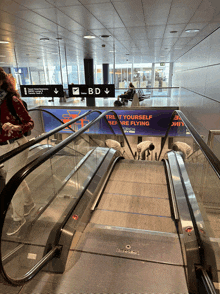 an escalator in an airport with a sign that says treat yourself before flying