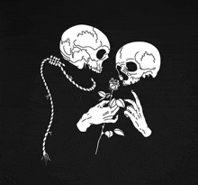 a couple of skulls are kissing each other and holding a rose .