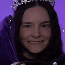 a woman wearing a tiara is smiling and holding a microphone