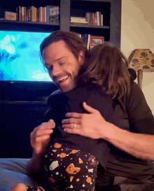 a man is hugging a little girl in front of a bookshelf that has a book called x-men franklin on it