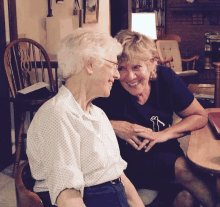 a woman wearing a shirt that says ' i love you ' on it sits next to another woman