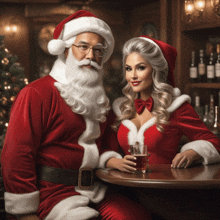 a man dressed as santa claus and a woman dressed as santa claus sitting at a table with a glass of beer