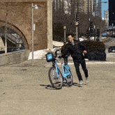 a man in a black jacket is riding a blue bike with a basket that says ' uber ' on it