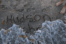 the word hudson is written in the sand near the water