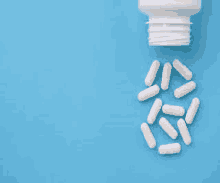 a white bottle of pills is pouring out of it on a blue background .