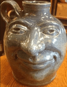 a blue vase with a face on it is on a wooden table