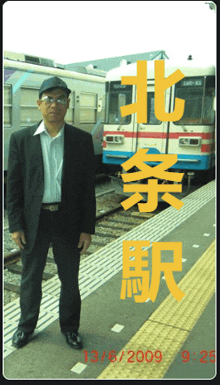 a man in a suit stands in front of a train with the date 13/6/2009