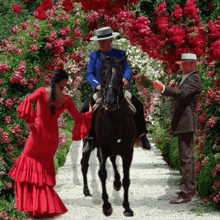 a woman in a red dress is standing next to a man on a horse