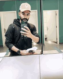 a man taking a selfie in a bathroom with a hat that says skull