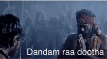 two men are standing next to each other in a dark room with the words dandam raa dootha written on the bottom .