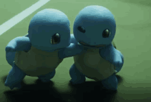 two blue cartoon turtles are standing next to each other on a tennis court .