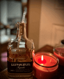 a bottle of lunazul tequila sits next to a red candle