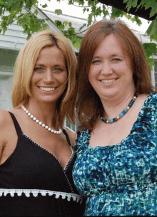 two women are posing for a picture and one has a pearl necklace on