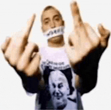 a man wearing a t-shirt with a picture of a man on it is giving the middle finger .