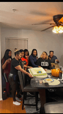 a woman wearing a nope sweatshirt cuts a cake