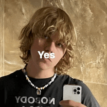 a young man with blonde hair is taking a selfie with a yes sign above his face .