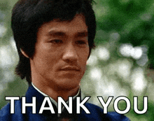 bruce lee is giving a thank you gesture with a blurred background .