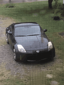 a black nissan sports car is parked in a gravel driveway