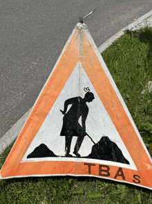 an orange and white sign that says tbas with a man digging