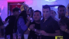 a group of people are standing around a bar in a nightclub .