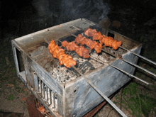 three skewers of meat are cooking on a grill made out of an old computer case