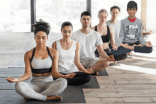 a boy wearing a fila shirt sits in a lotus position with other people