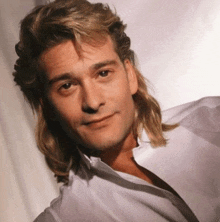 a man with long blonde hair and a white shirt