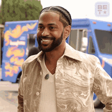 a man with a beard is smiling in front of a blue food truck that says ' shack ' on it