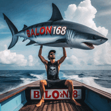 a man sitting on a boat holding a shark that says balon168