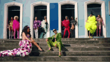 a woman in a floral dress sits on a set of stairs next to a man in a leopard print suit