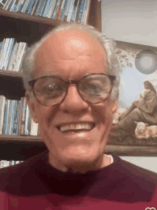 a man wearing glasses is smiling in front of a picture of jesus