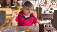 a young boy in a red polo shirt is sitting at a table with a box of candy on it