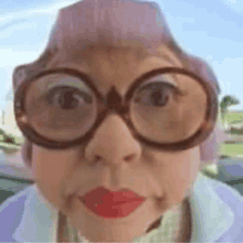 a close up of an elderly woman wearing glasses and red lips .