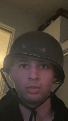 a young man wearing a military helmet looks at the camera in a dark room