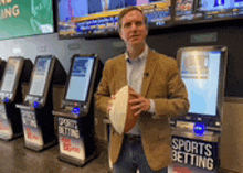 a man is holding a football in front of a sports betting machine