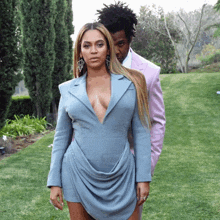 a woman in a blue dress and a man in a pink suit pose for a photo