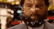 a man with a beard is looking at a computer screen with mathematical equations written on it .