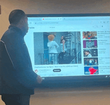 a man stands in front of a computer screen that says youtube on it