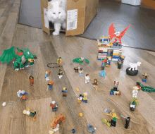 a cat is sitting in a box surrounded by lego toys