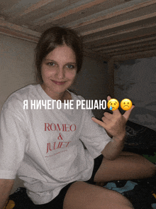 a girl wearing a romeo and juliet t-shirt makes a peace sign