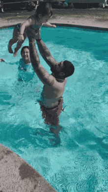 a man is holding a child in his arms in a pool