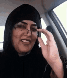 a woman wearing a hijab and glasses is talking on a cell phone .