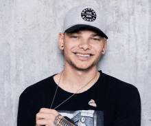 a man wearing a brixton supply hat and a black shirt smiles