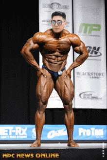 a bodybuilder stands on a stage in front of a banner that says npc news online