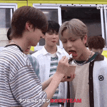 a group of young men are standing in front of a food truck and one of them is eating a piece of meat