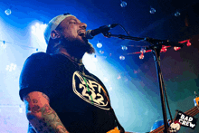 a man singing into a microphone with a bad crew banner in the background