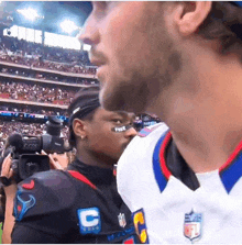 a man wearing a jersey with the letter c on it is talking to another man