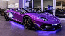 a purple lamborghini aventador is parked in a car showroom .