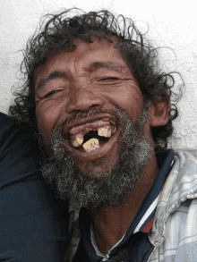 a man with a beard and missing teeth is smiling with his eyes closed