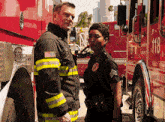 a man and a woman are standing in front of a red fire truck with the number 118 on it